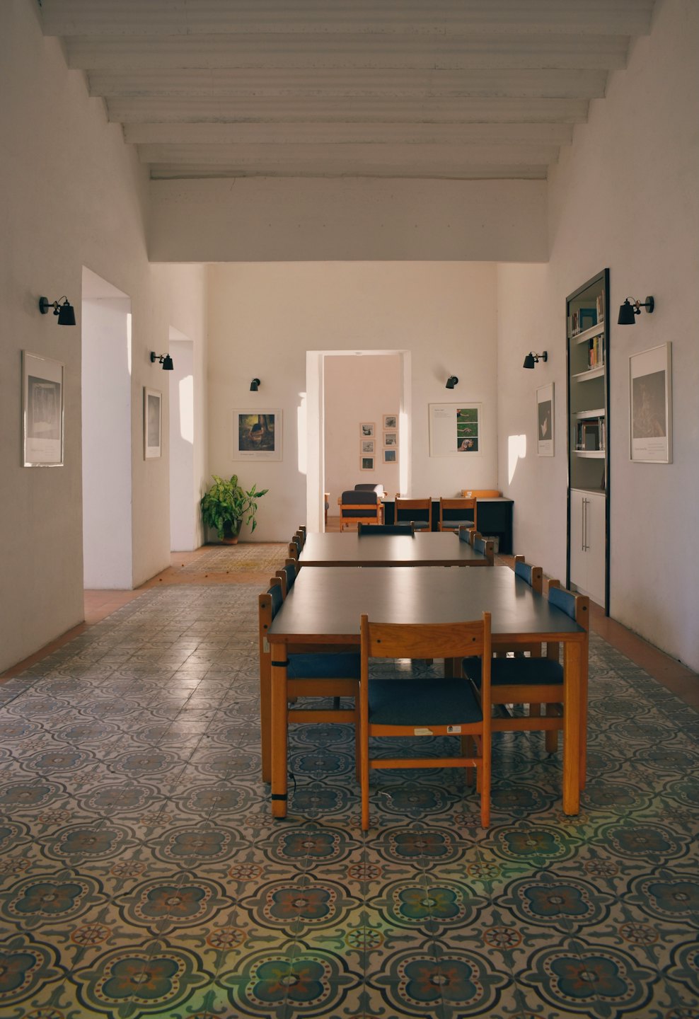 Empty study room with long wooden tables and blue chairs.