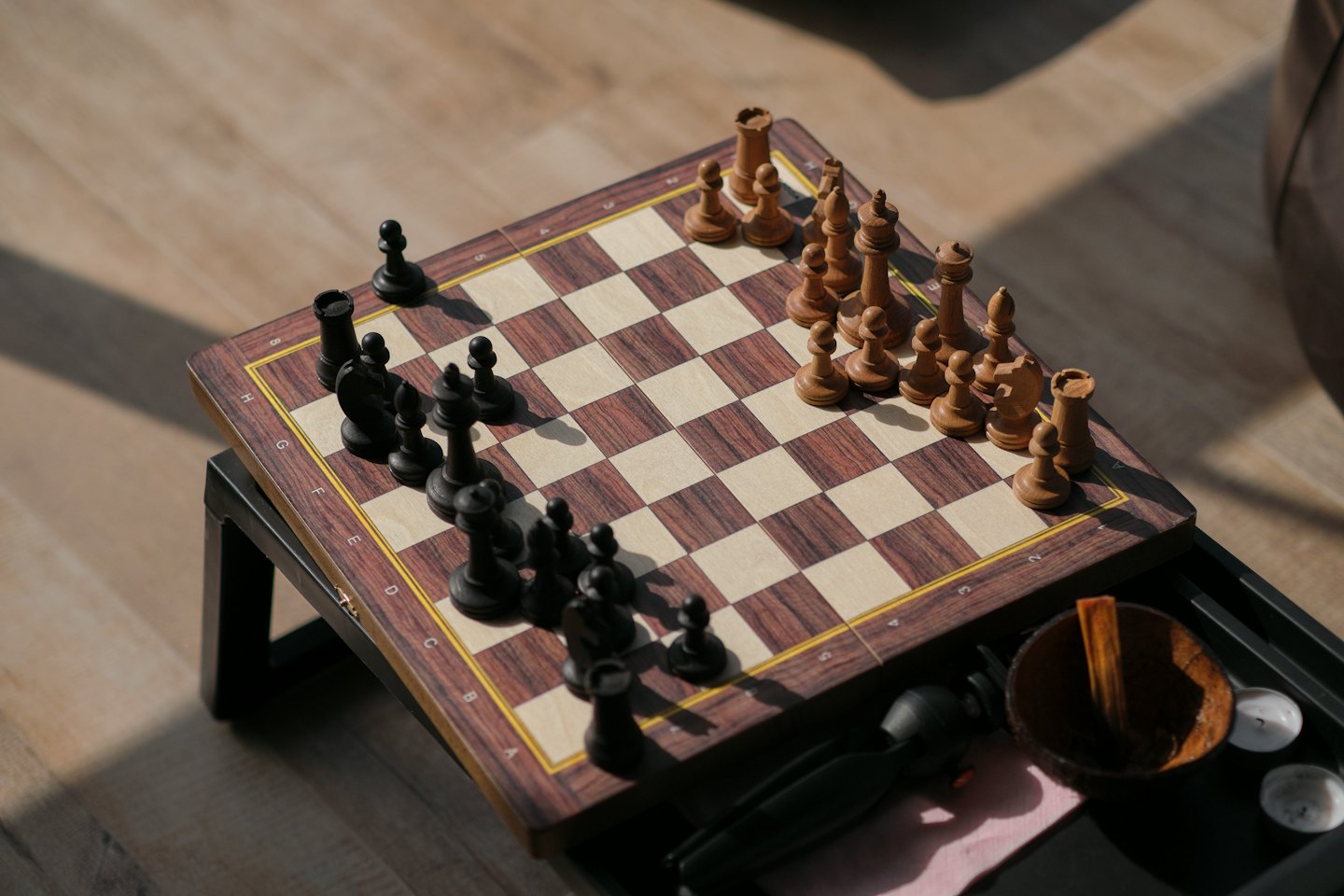 Wooden chessboard with pieces set up on a minimalist table.