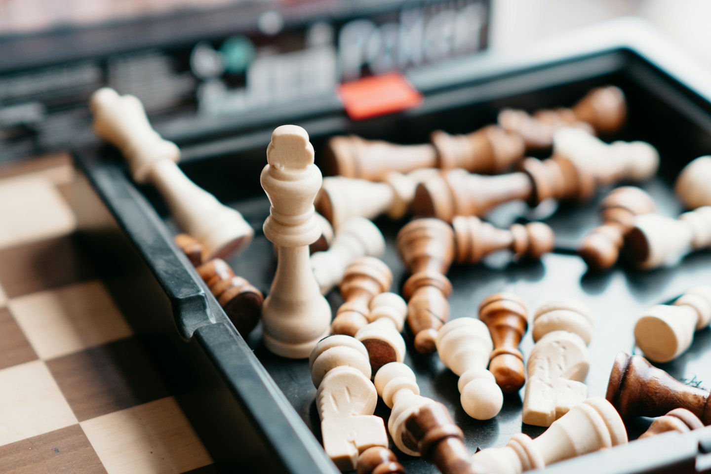 A white king stands among scattered wooden chess pieces.