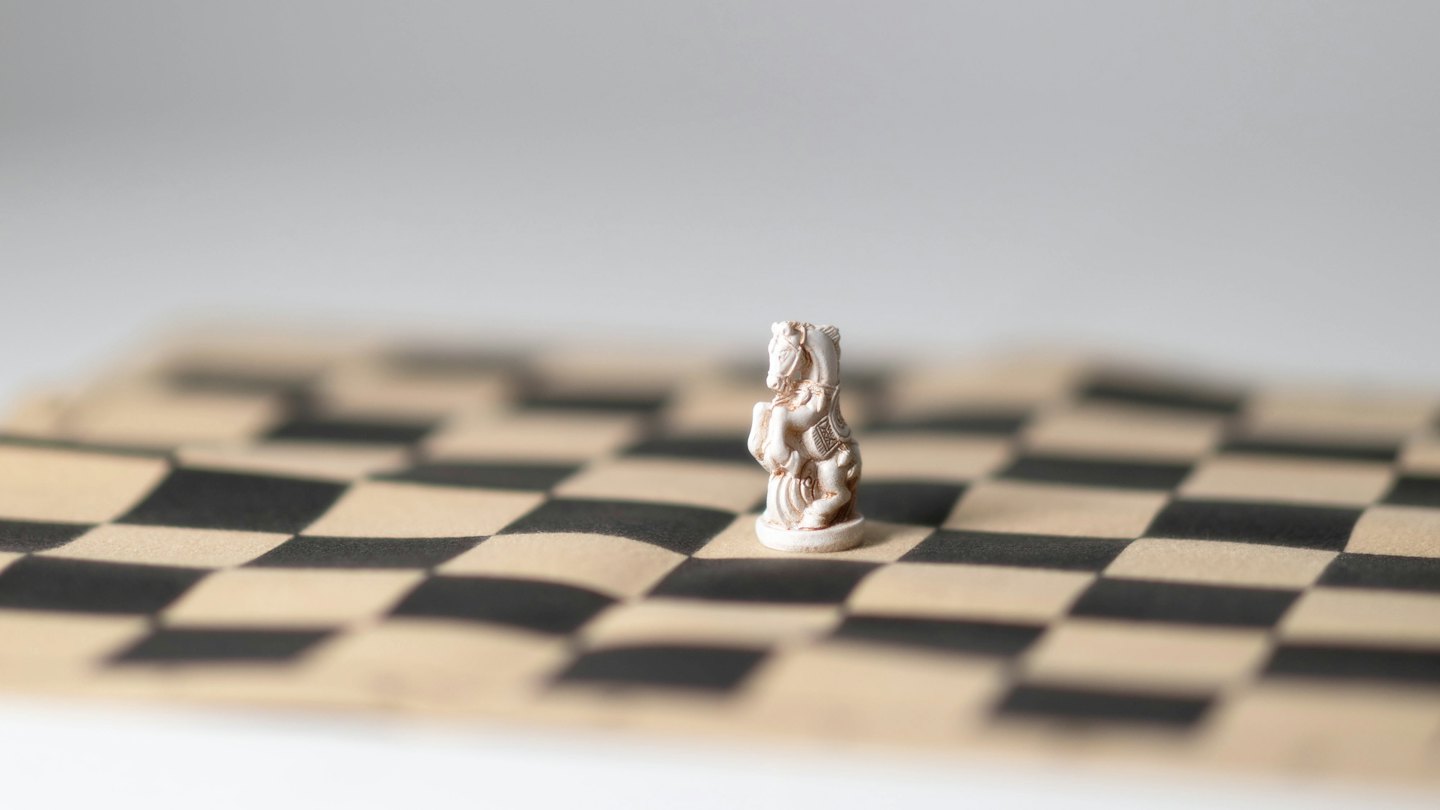 White chess knight on a checkered board.