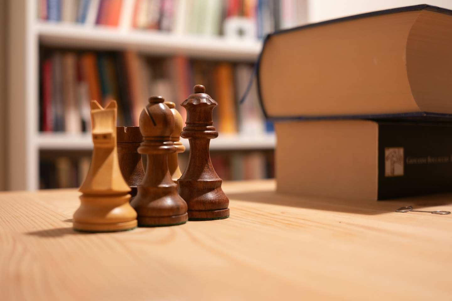Wooden chess pieces arranged on a light wooden table.