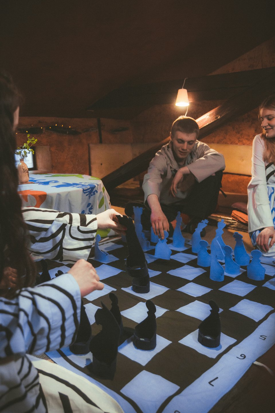 Three people playing an oversized chess game on the floor.