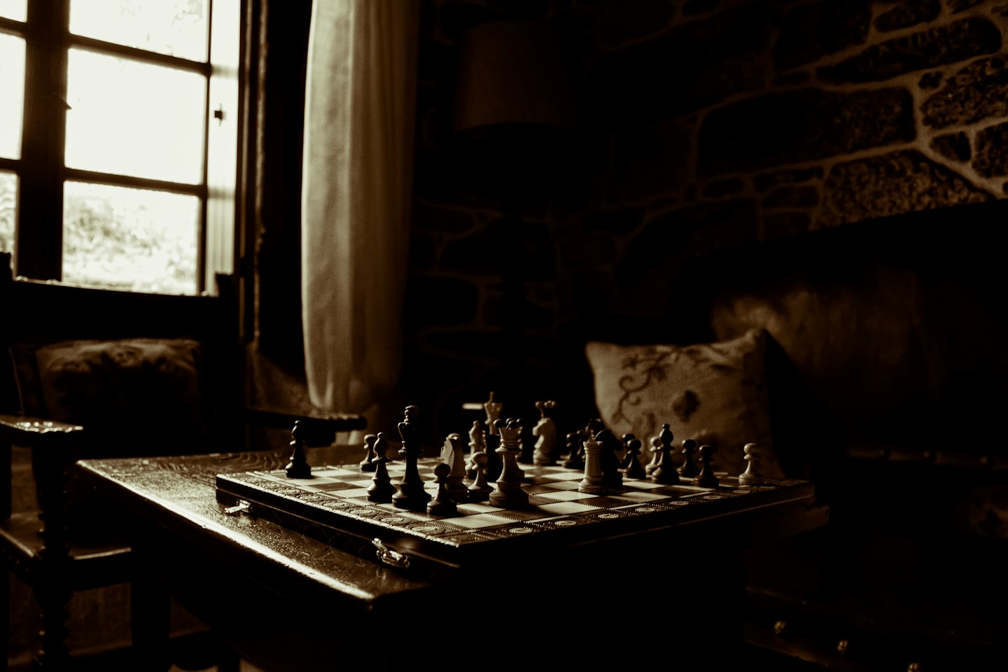 Wooden chessboard with pieces set up on a polished table.